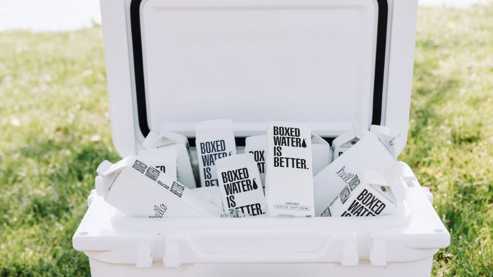 Boxed water ice cooler on the grass in front of the water.