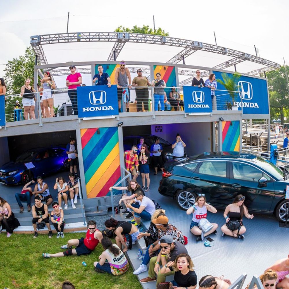 Honda stage with a car and people sitting around it.